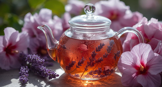 A beautiful glass jar filled with a deep-red Fresh Lavender Hibiscus Infusion, showing sprigs of fresh garden mint and purple lavender blossoms.