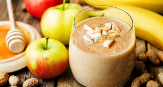A thick and creamy Nut Butter Smoothie in a glass, served next to fresh apple slices and a jar of almond butter, inspired by a Seasonal Garden Kit harvest.